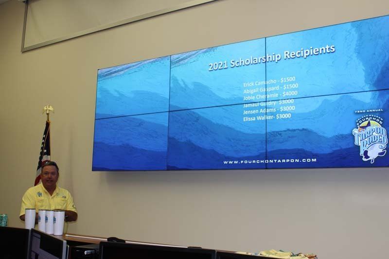 A man in a yellow shirt is standing in front of a large screen.