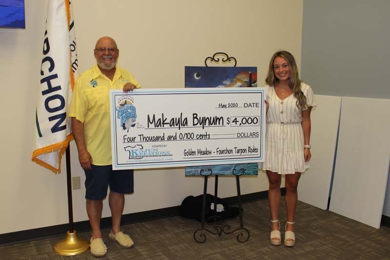 A man and a woman are holding a large check in a room.