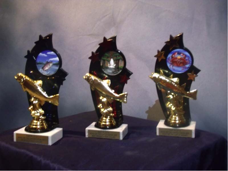 Three trophies with fish on them are on a table