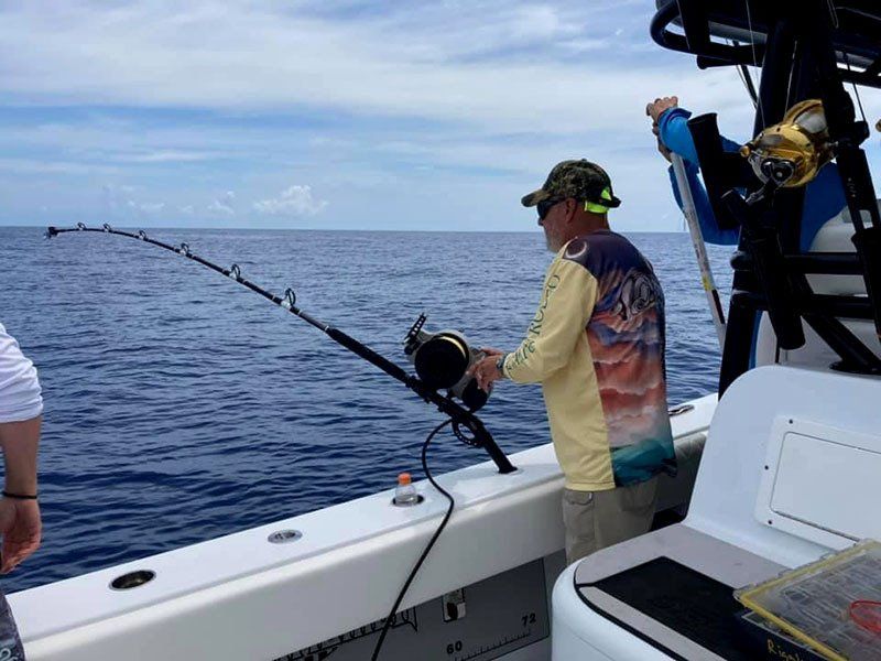 A man is fishing on a boat in the ocean