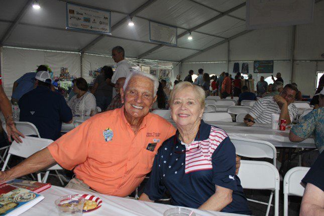 A man and woman are posing for a picture while sitting at a table in a tent.