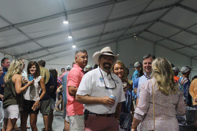 A group of people are standing in a tent talking to each other.