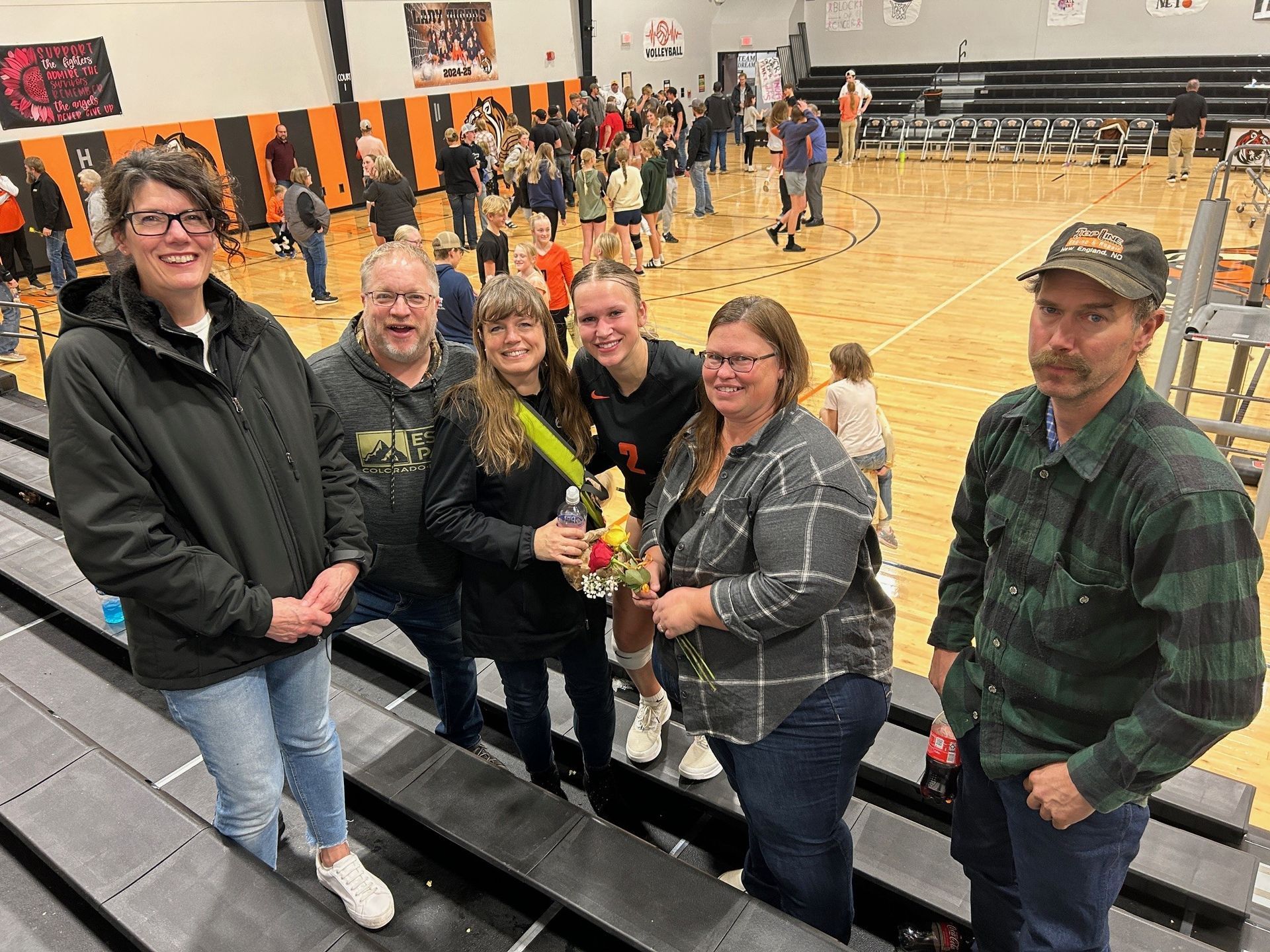 A group of people are posing for a picture in front of a basketball court.