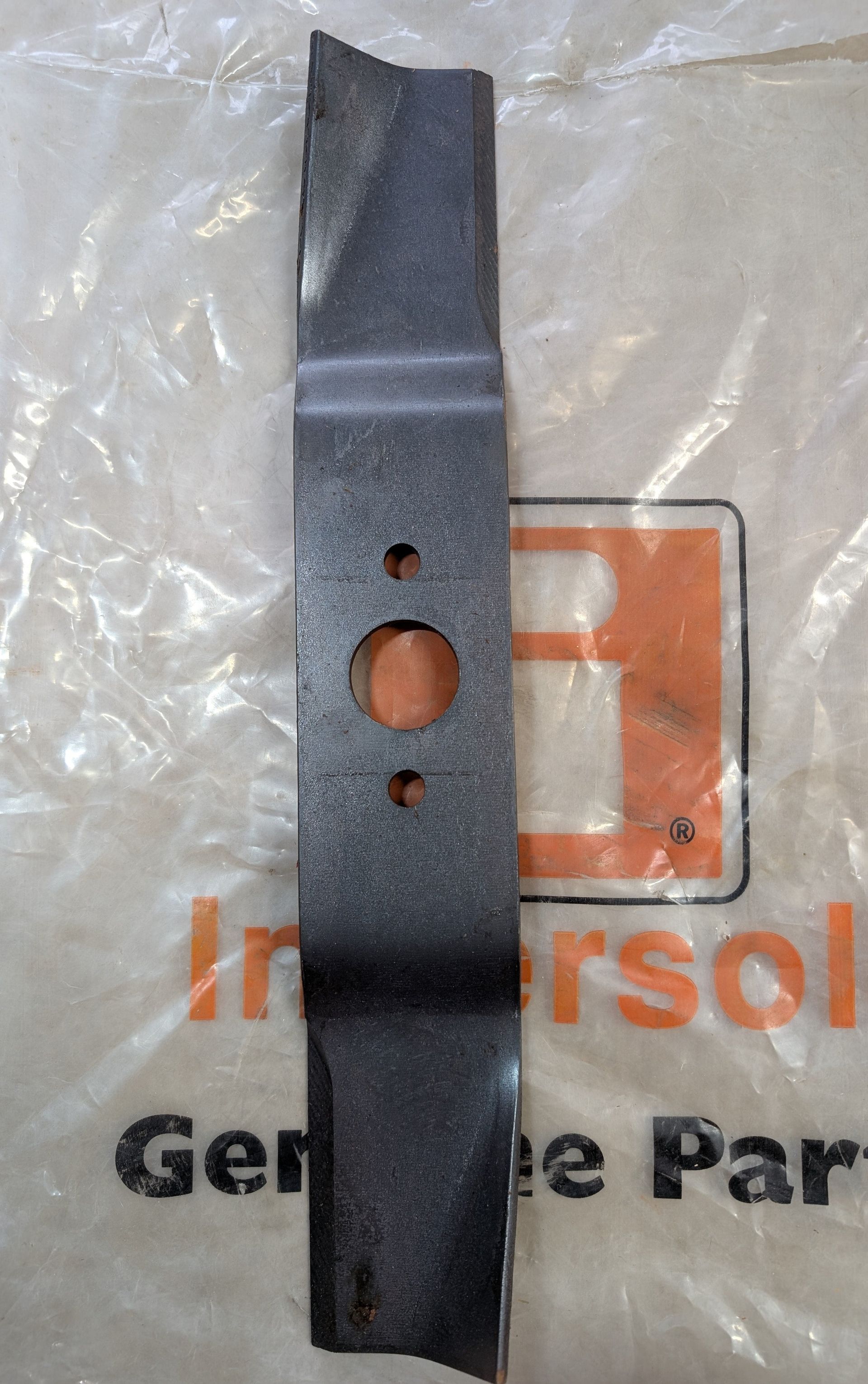Black metal bracket with two holes lying on an Ingersoll Genuine Parts package.