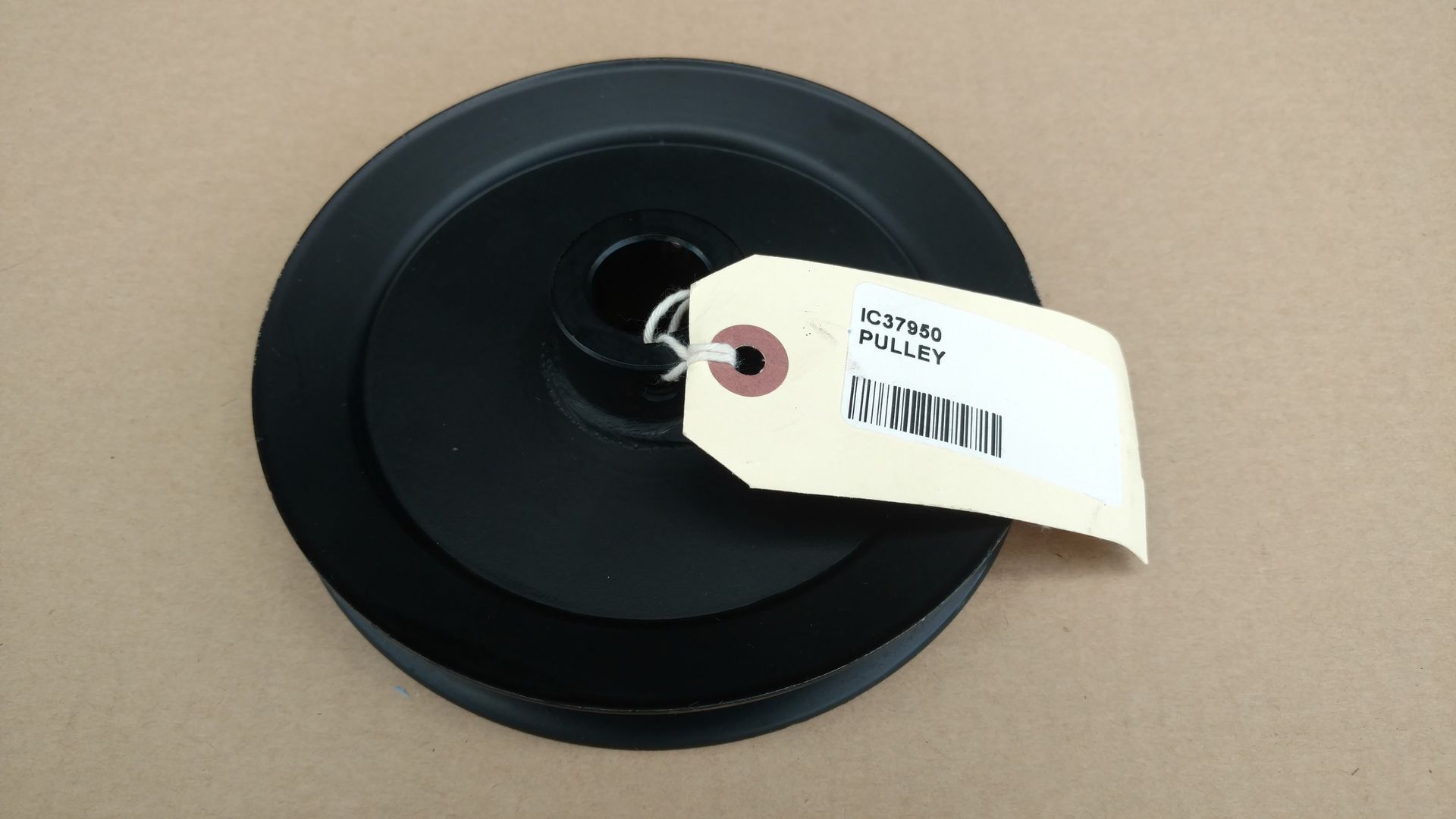 Black circular spool with a white tag on a beige surface