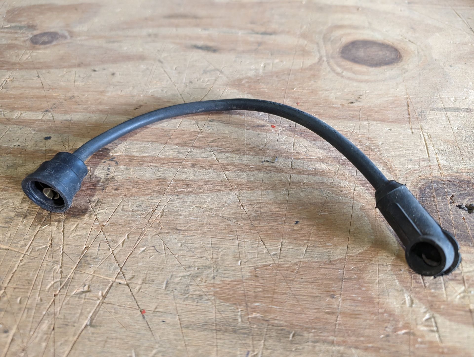 Black curved cable with connectors on a wooden surface