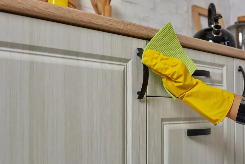 Person in Yellow Gloves Cleaning Kitchen Cabinet With a Green Cloth — Jamac Cleaning Services in Lake Macquarie, NSW