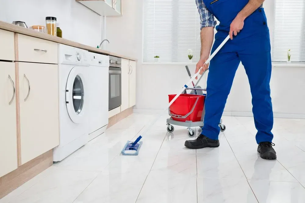 Person in Blue Overalls Mopping a Kitchen Floor — Jamac Cleaning Services in Toronto, NSW