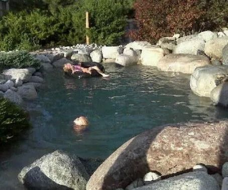 A woman is laying on a rock in a pond surrounded by rocks.