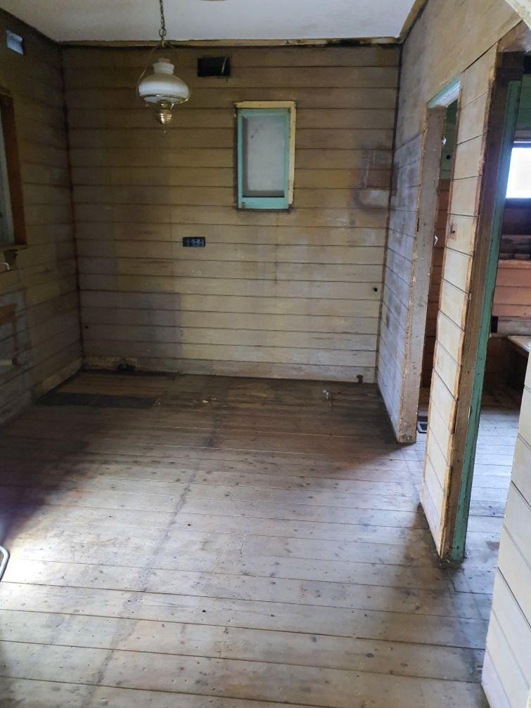 An empty room with wooden floors and a lantern hanging from the ceiling.