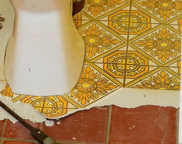 A toilet with a yellow and white tile floor