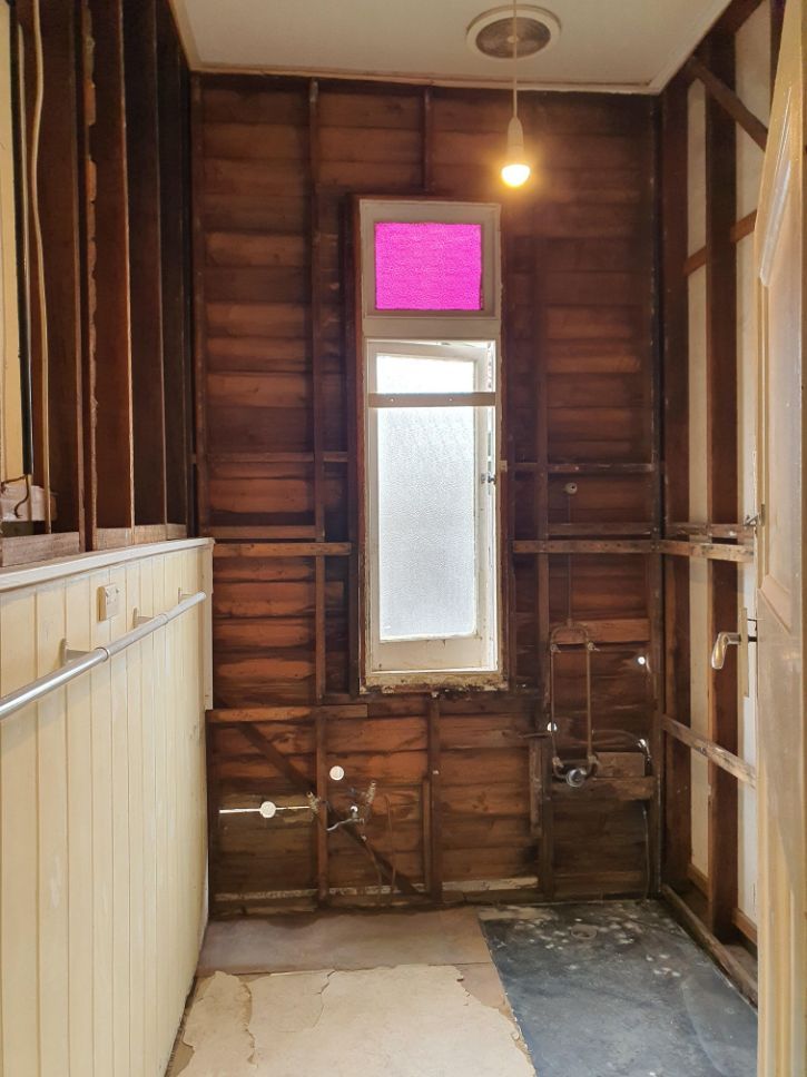 A bathroom with wooden walls and a pink window.
