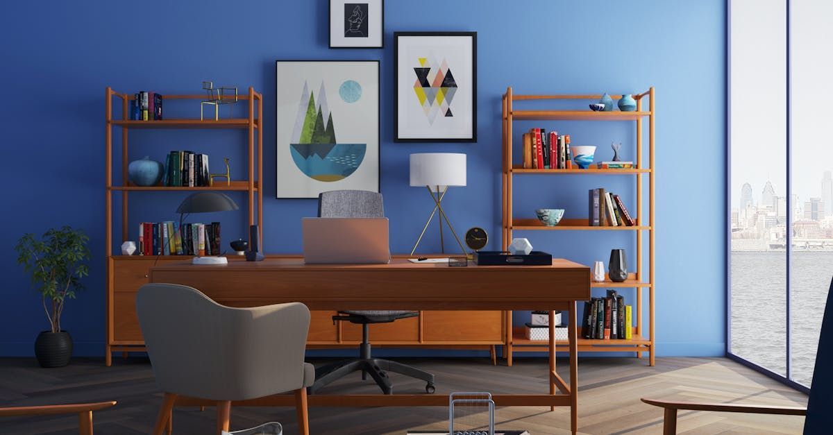 A home office with blue walls , a desk , chairs , shelves and a laptop on it.