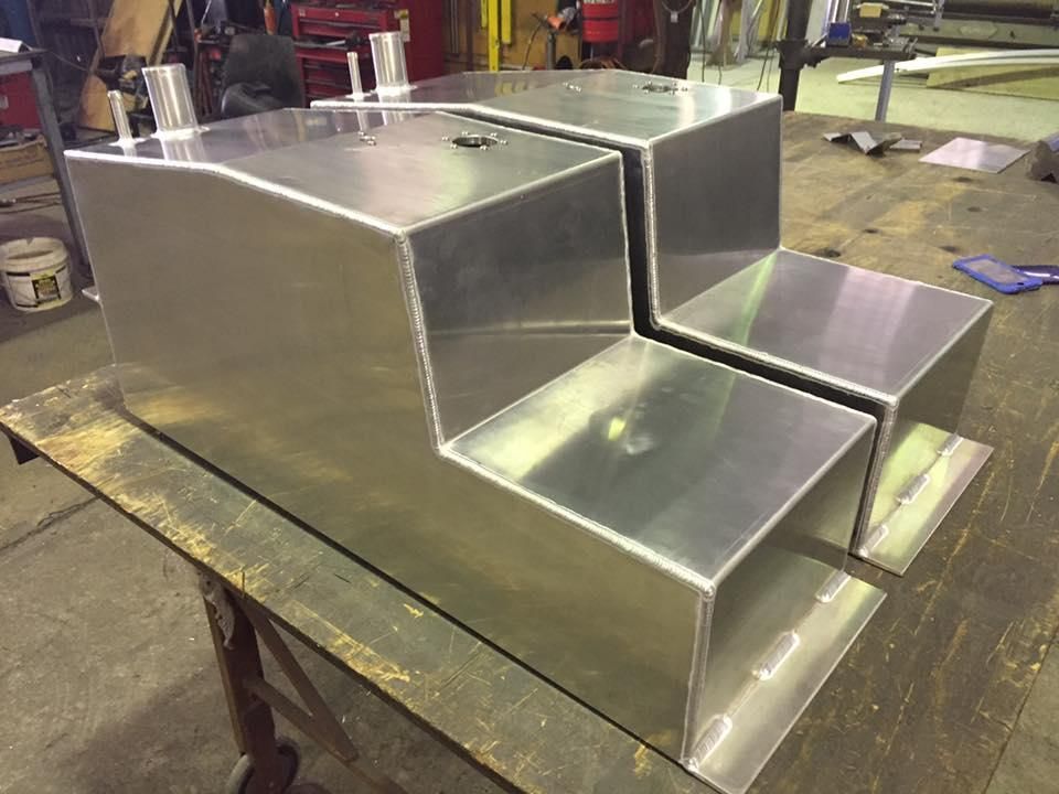Two Aluminium Tanks Are Sitting on Top of A Wooden Table — Shearwater Engineering in Taree, NSW