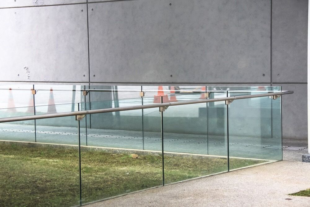 A glass Fence Surrounds a Grassy area in front of a Building — Shearwater Engineering in Port Macquarie, NSW