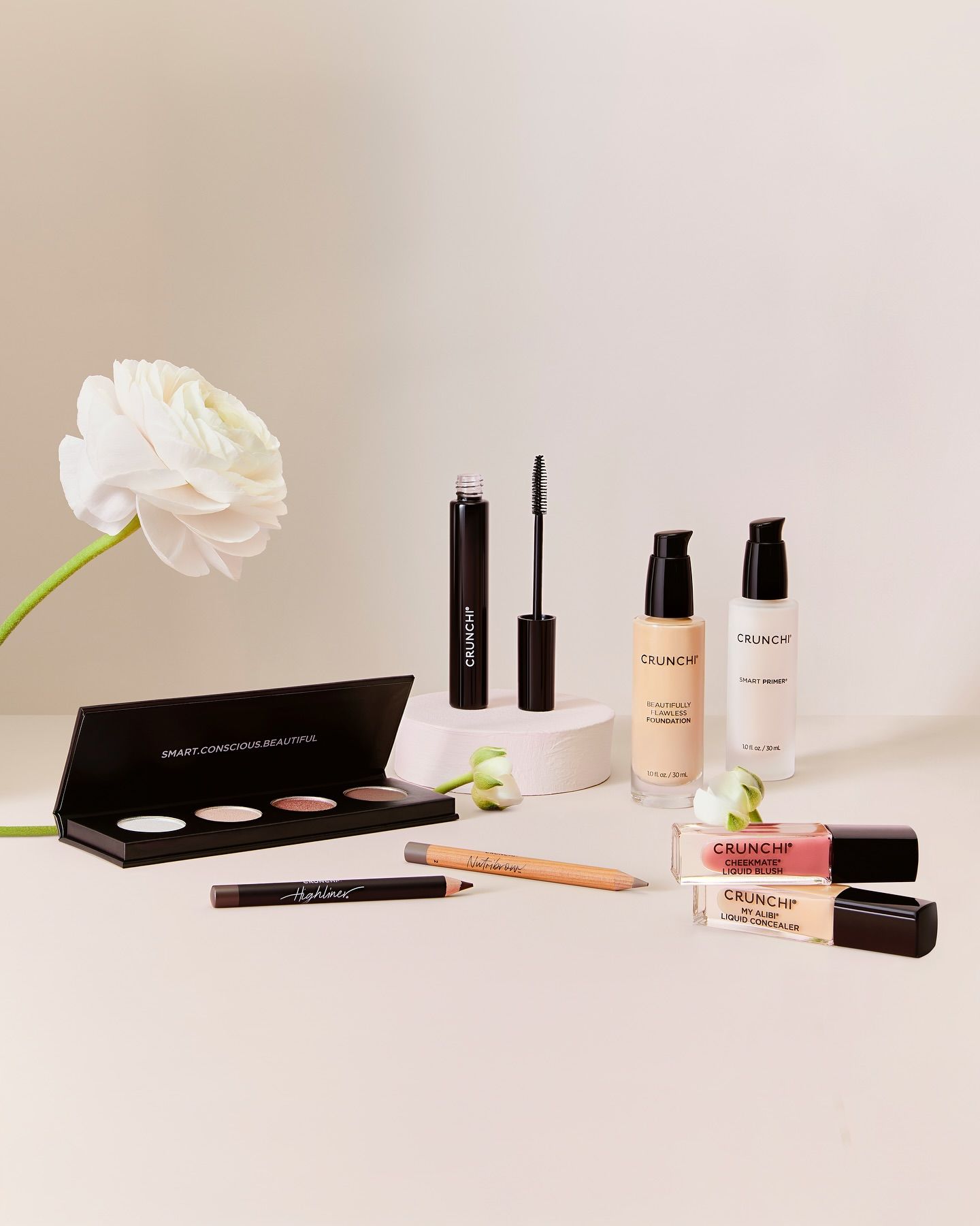 Crunchi makeup products lined up against a white background with flower