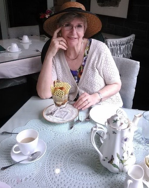 A woman wearing a hat is sitting at a table with a cup of coffee