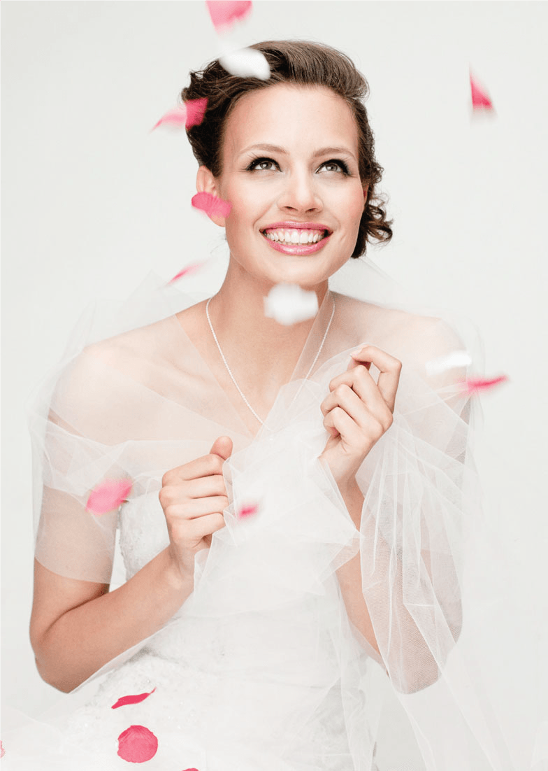 A woman in a wedding dress is surrounded by rose petals