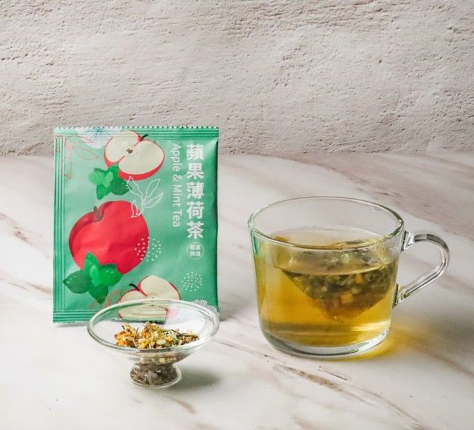 淺色大理石桌面上放著一個茶包、一小碗散裝茶葉和一杯泡好的茶。