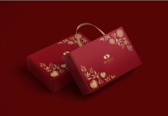 兩個長方形的深紅色禮盒，飾有優雅的金色花卉圖案和絲帶提手，背景也是紅色的。