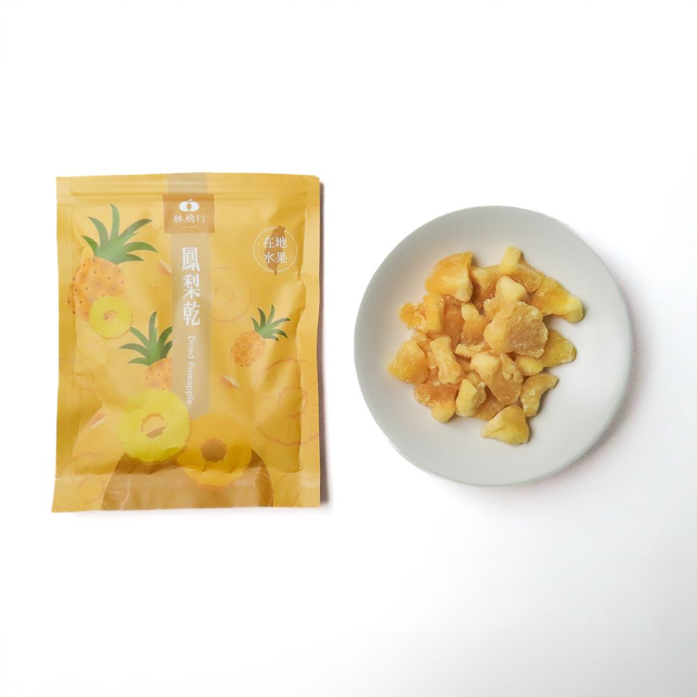 一袋打開的黃色鳳梨主題零食袋裡，散落著幾塊鳳梨乾，掉落在白色背景上。