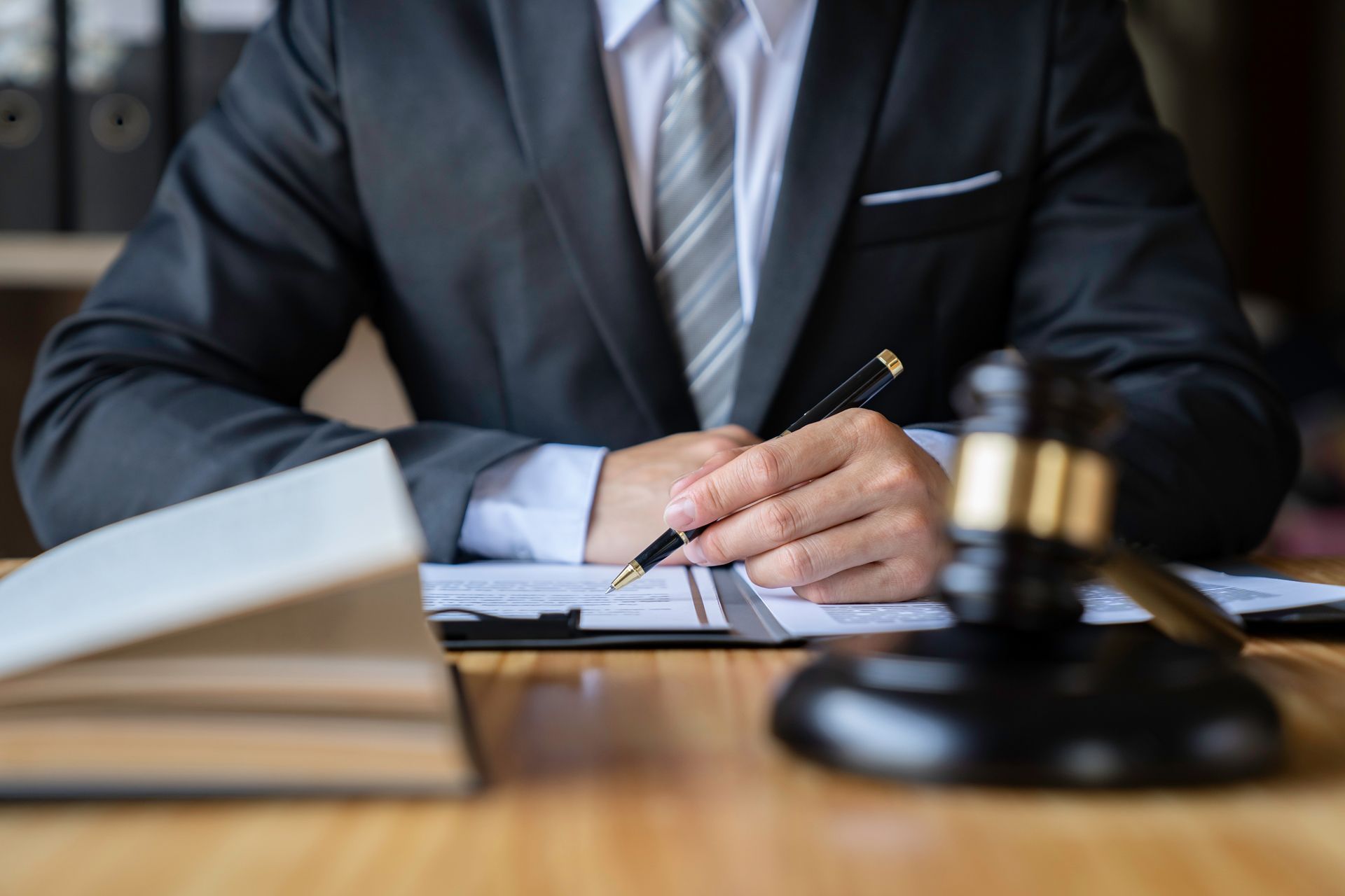 Lawyer in suit writing at desk with gavel and documents.