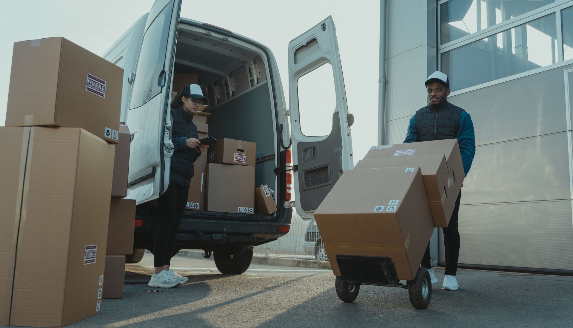 Two delivery men are loading boxes into a van.