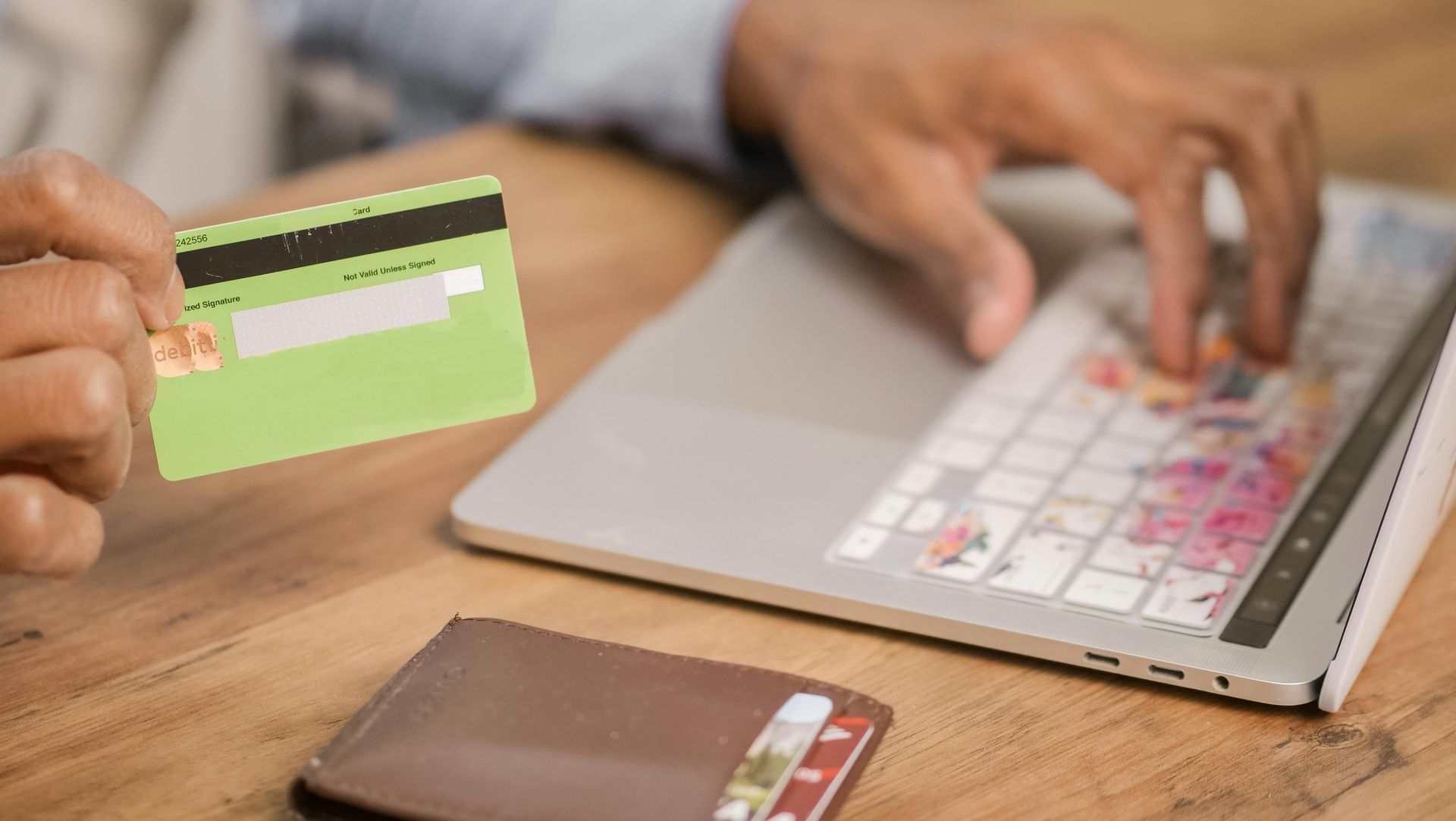 A person is holding a credit card in front of a laptop computer.