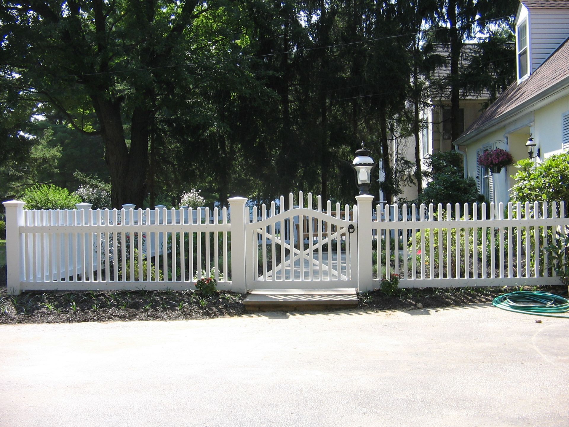 A white picket fence with a gate in front of a house