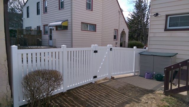 A white fence is sitting in front of a house.