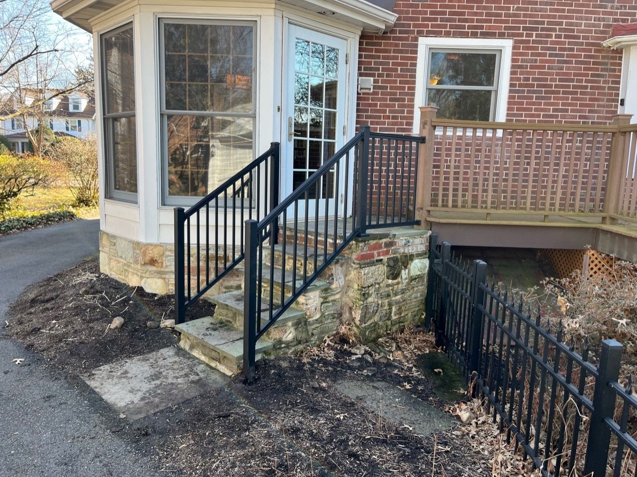 A brick house with a black fence and stairs leading to it.