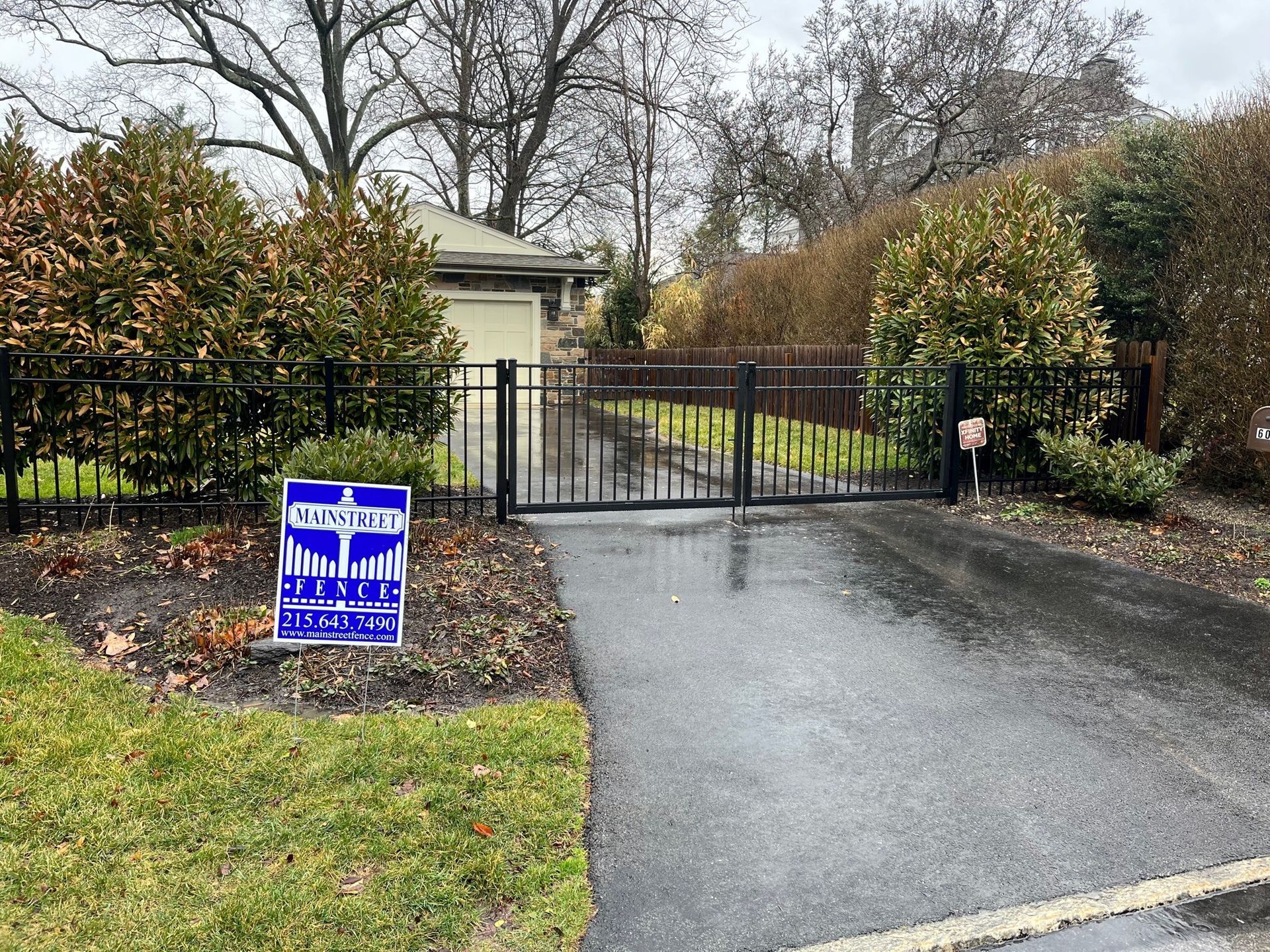A blue sign is sitting on the side of a road next to a gate.