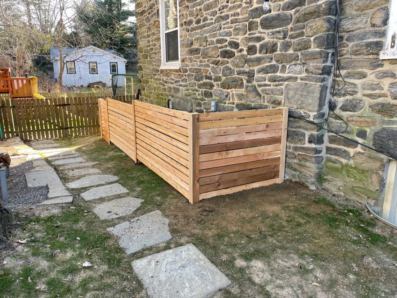 A wooden fence is sitting in front of a stone building.
