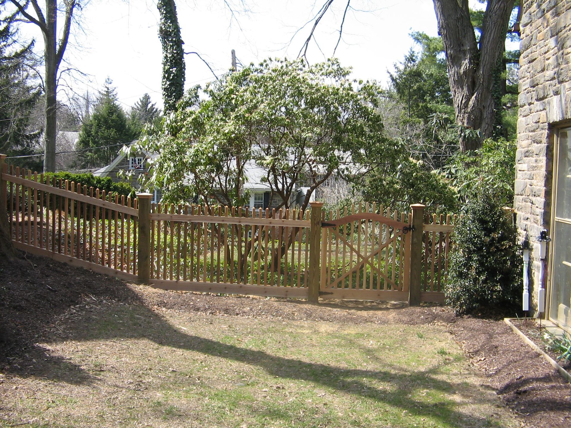 A wooden fence surrounds a yard with trees in the background