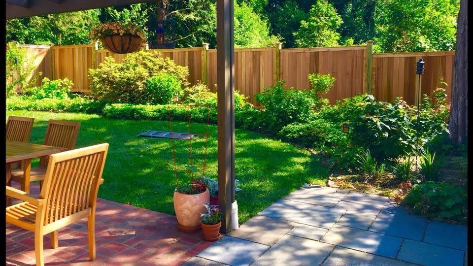 A wooden fence surrounds a patio with a table and chairs