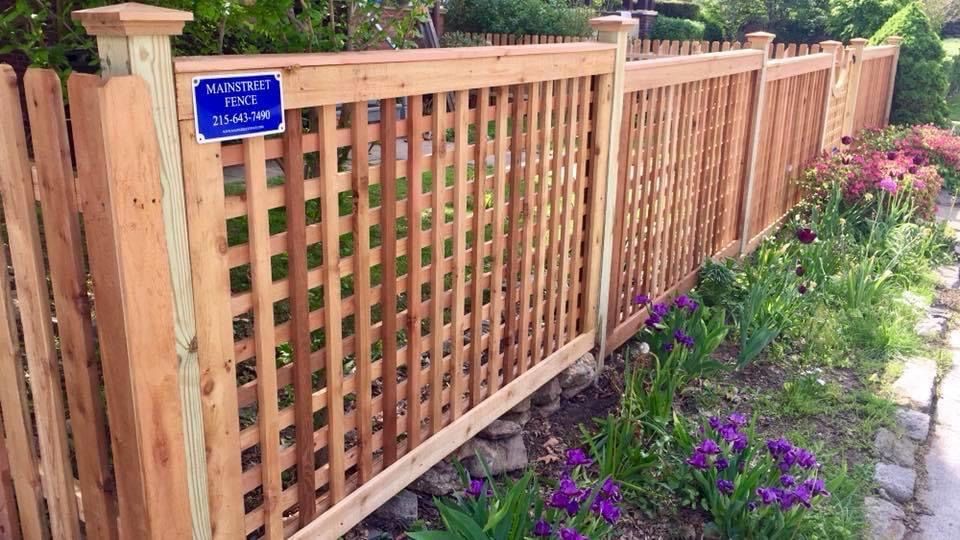 A wooden fence surrounds a garden with purple flowers.