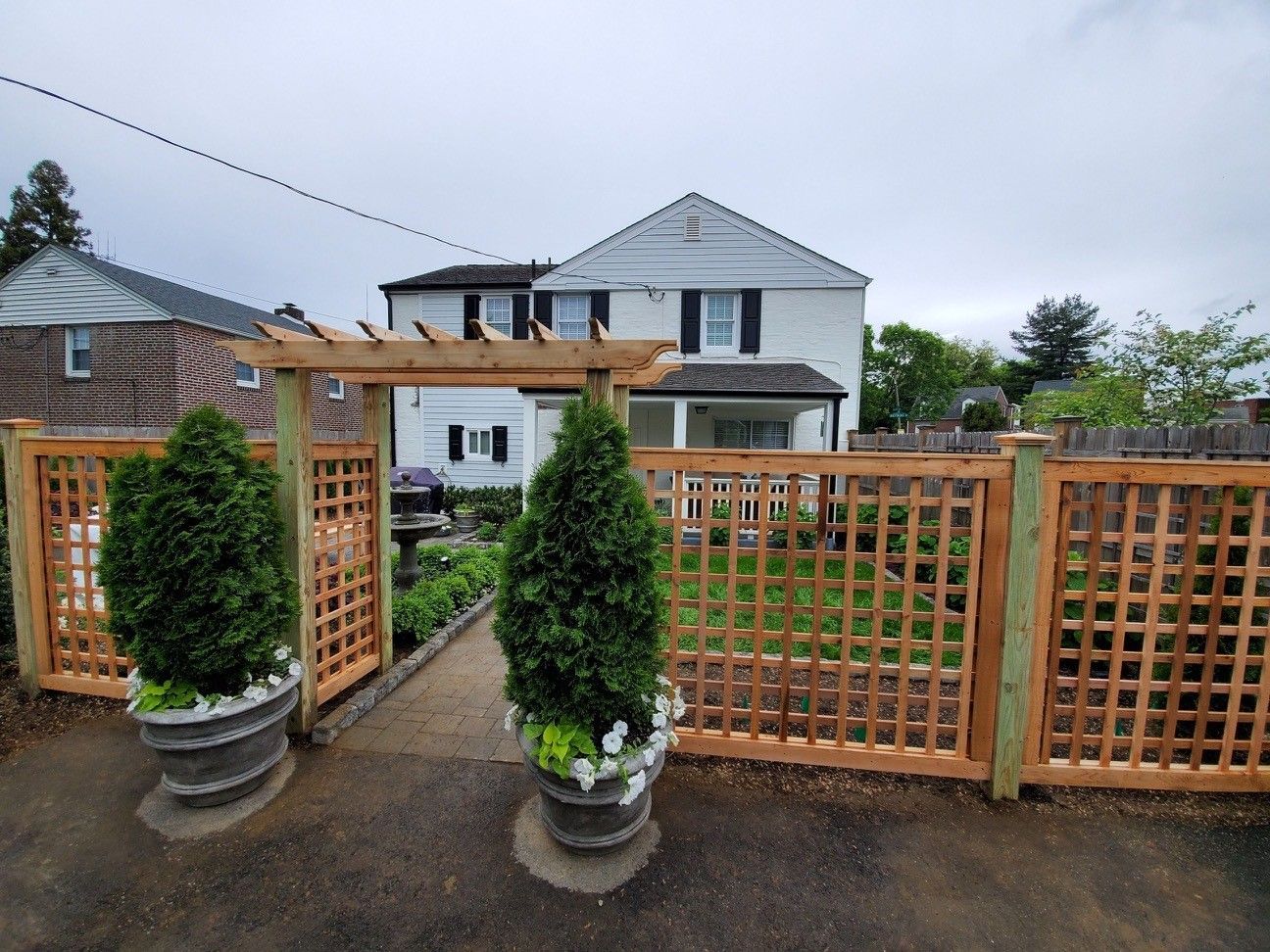 A wooden fence with potted plants in front of a house.