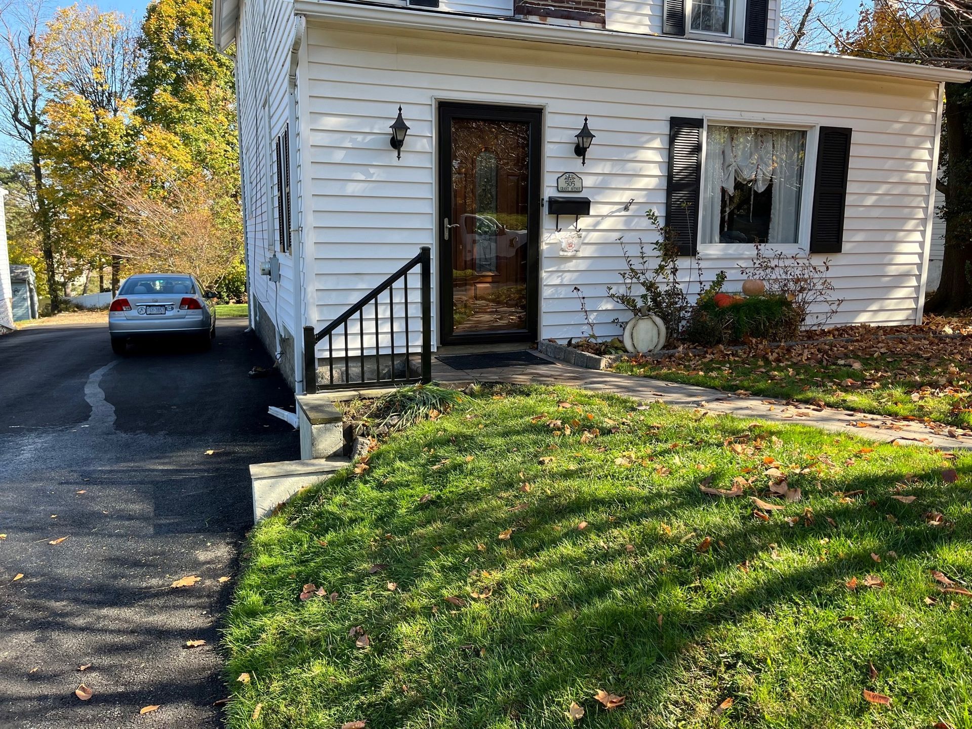 A white house with a car parked in front of it.