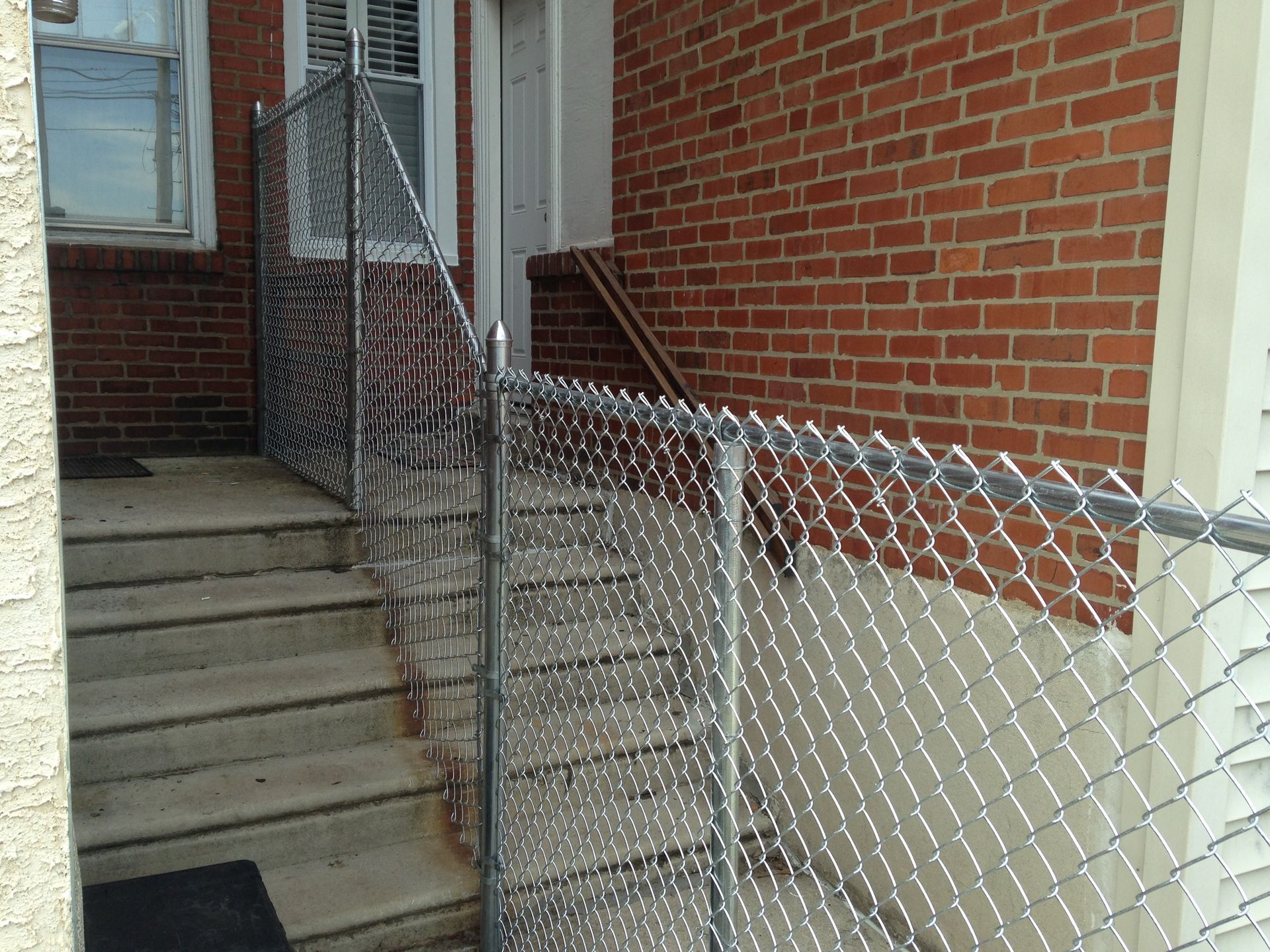 A chain link fence surrounds a set of stairs leading up to a brick building.
