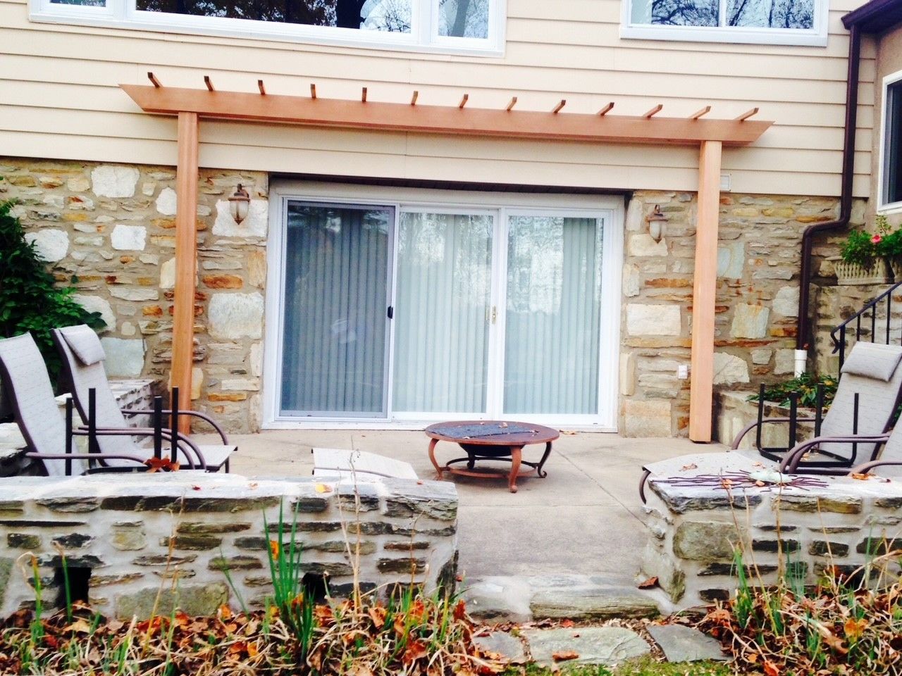 A patio with a pergola and a fire pit in front of a house