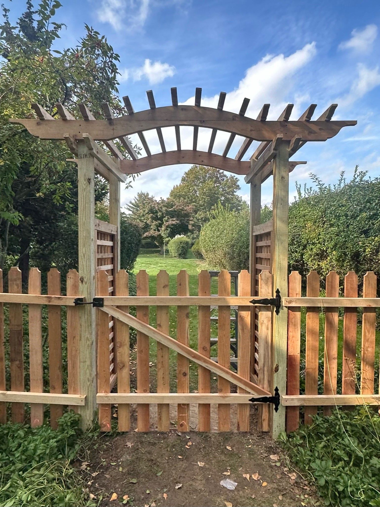 A wooden gate with a pergola on top of it.