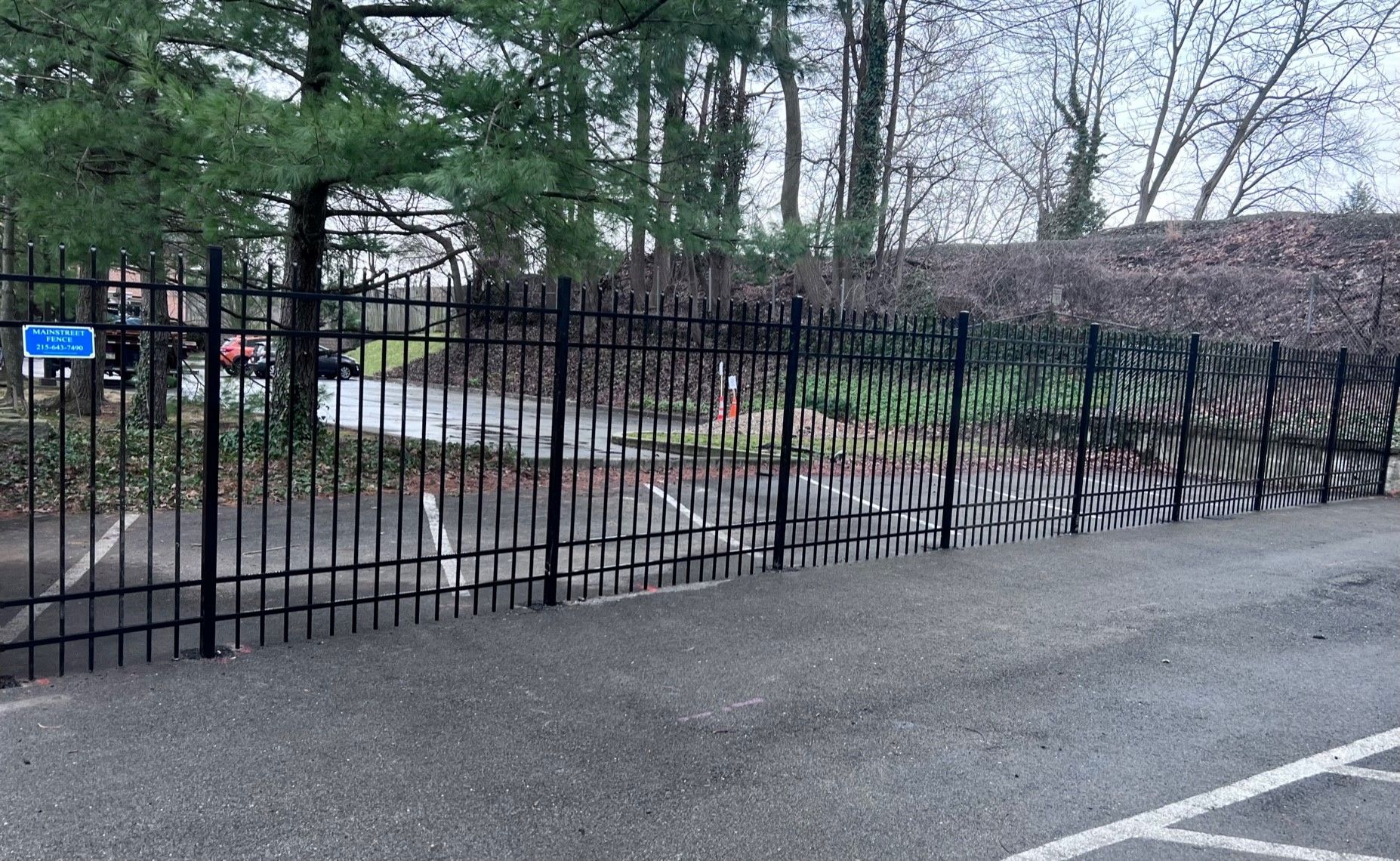 A black wrought iron fence surrounds a parking lot.
