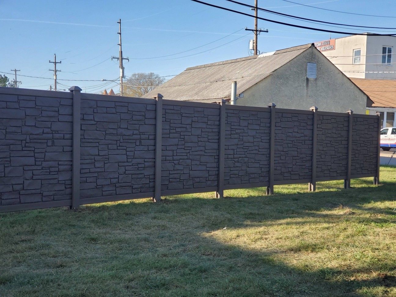 A fence is sitting in the middle of a grassy field in front of a house.