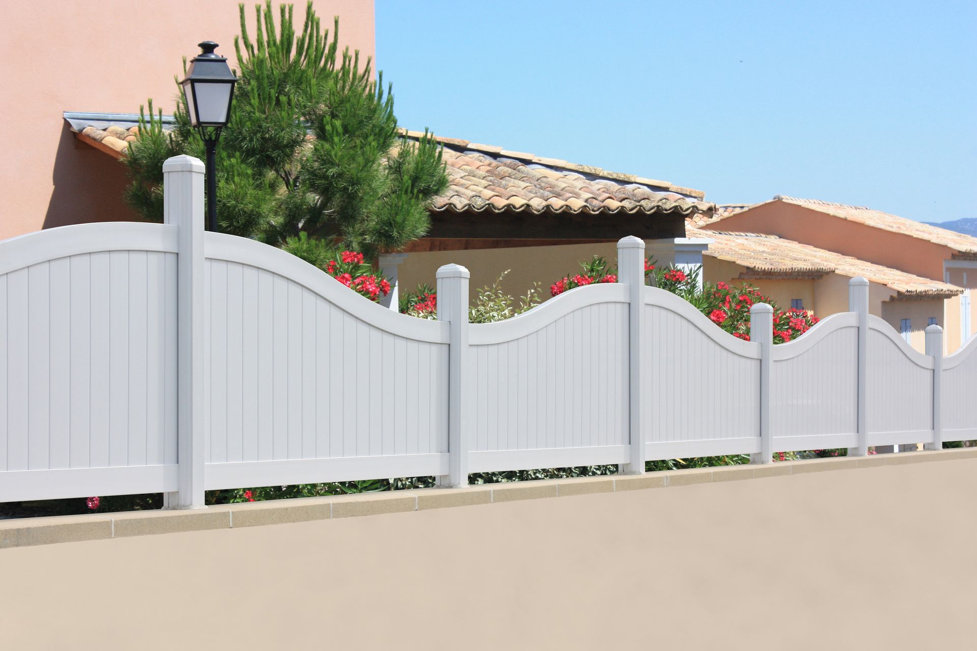 White PVC fence in front of a garden, covering it from view.