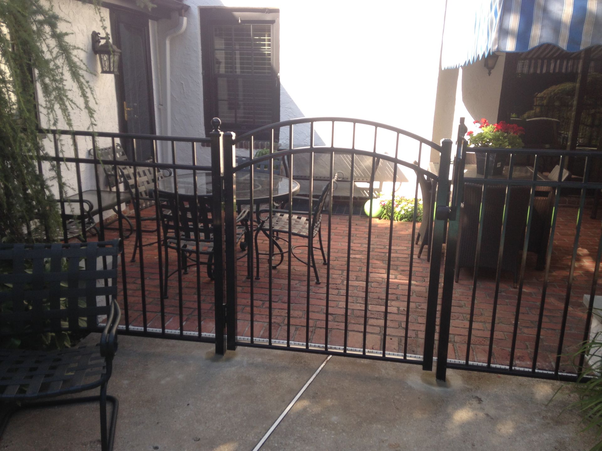 A black fence surrounds a patio with a table and chairs