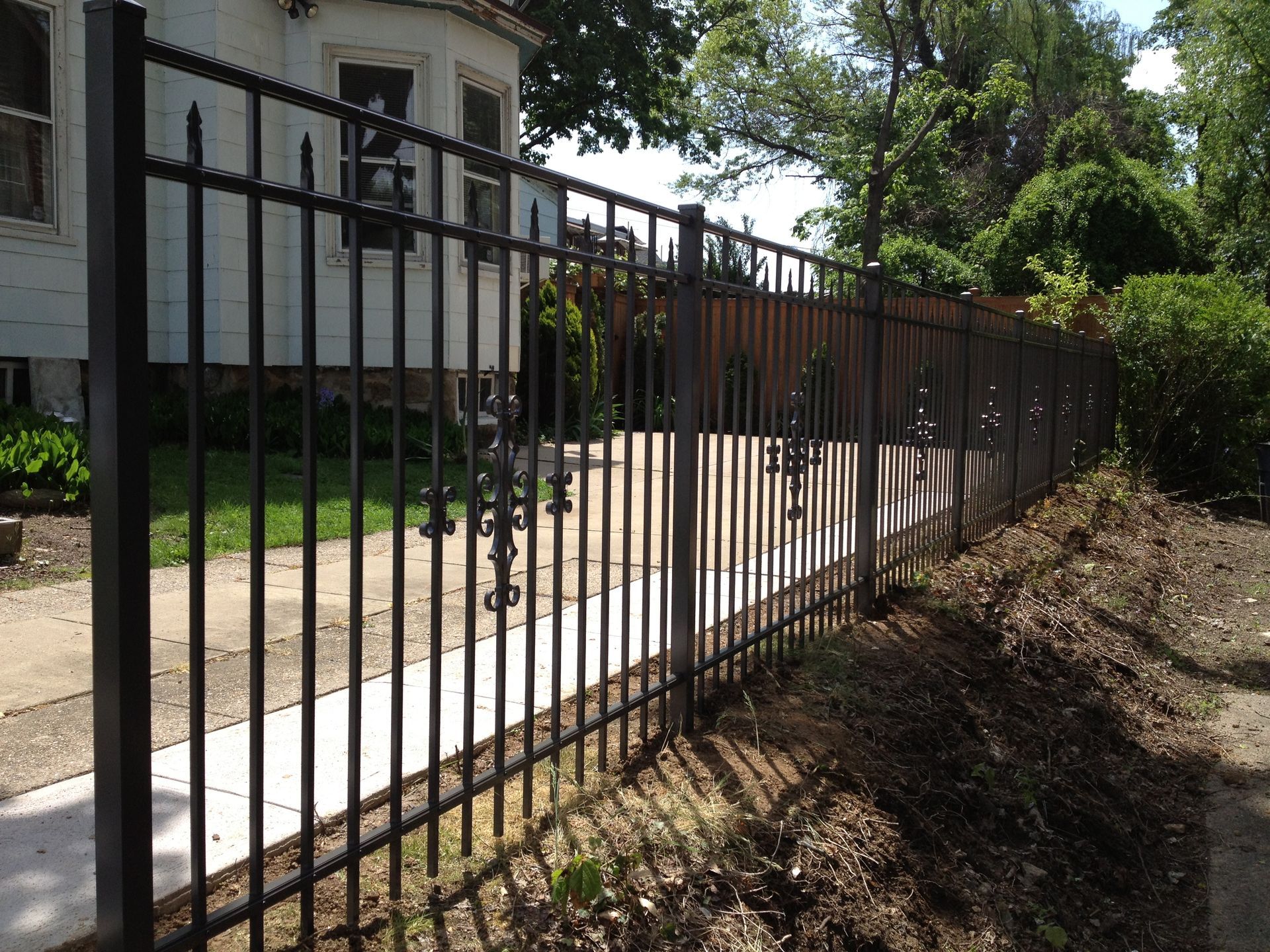 A black metal fence surrounds a white house