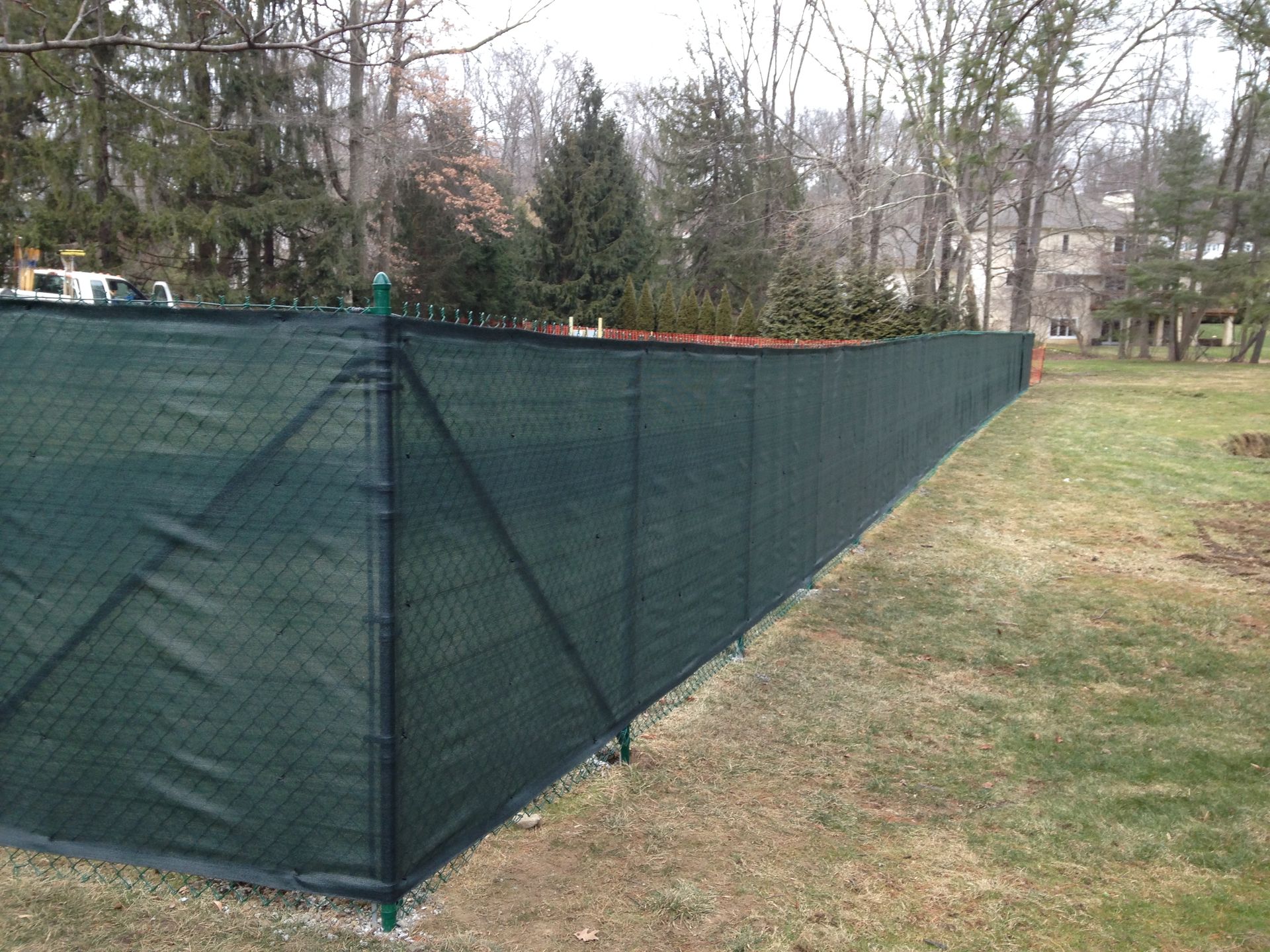 A chain link fence with a green shade cloth attached to it