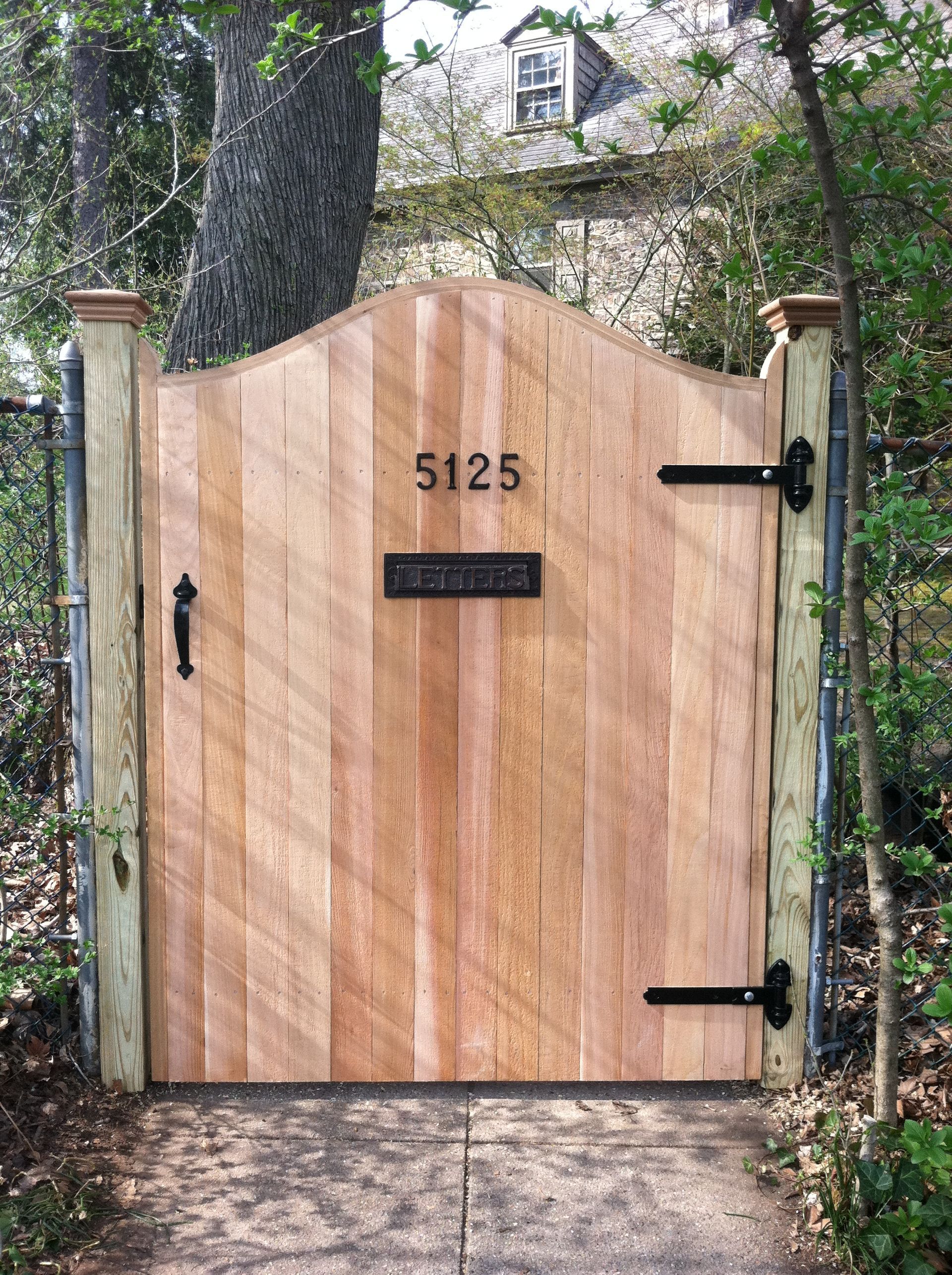 A wooden gate with the number 5125 on it is surrounded by trees.