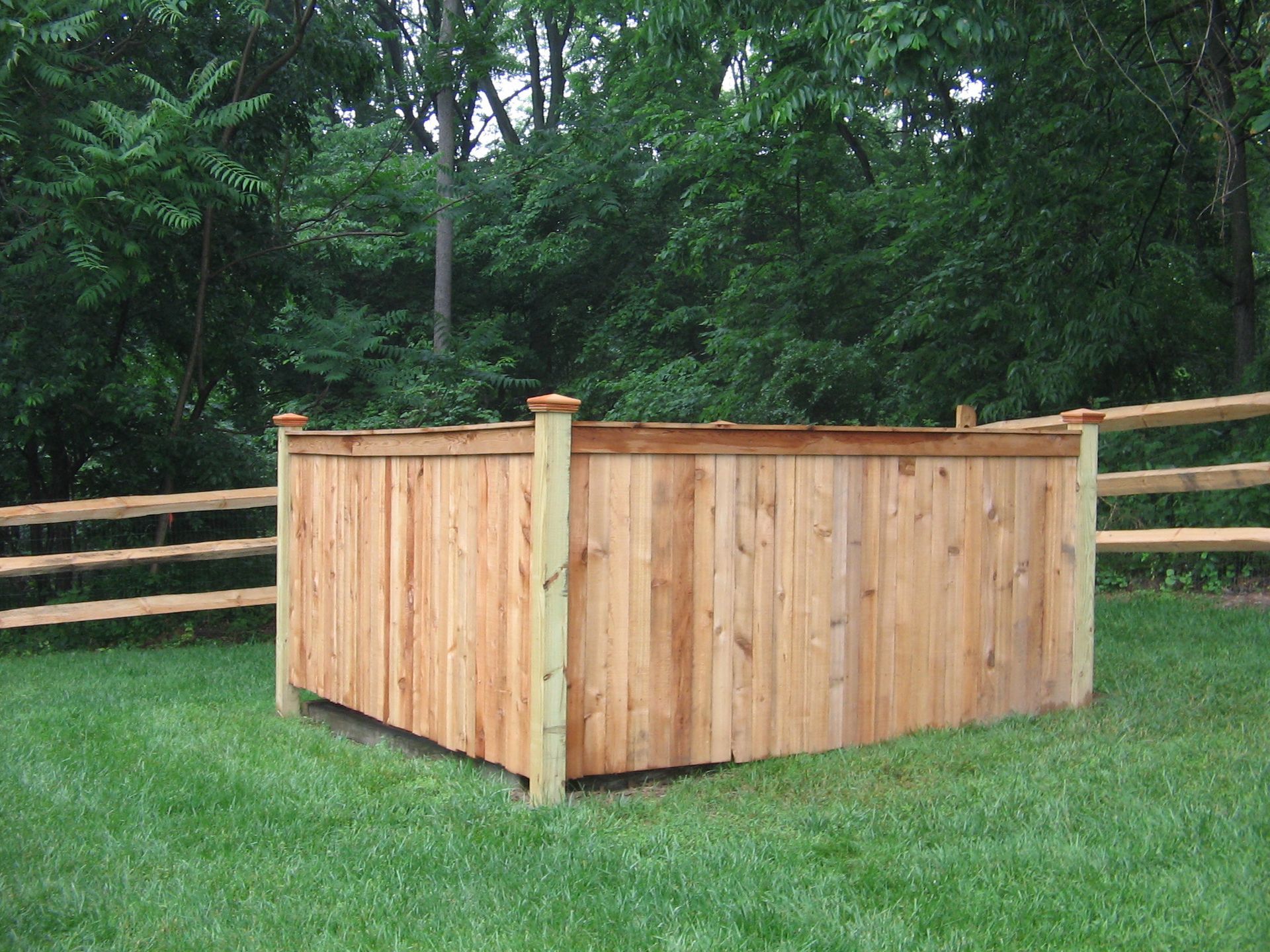 A wooden fence is in the middle of a lush green field