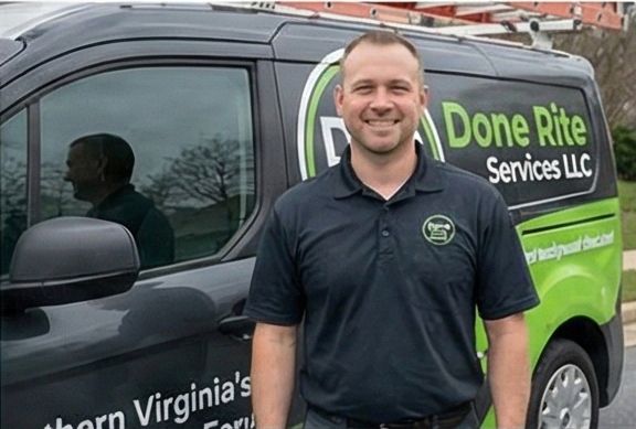 Man in black shirt smiles next to a van with 
